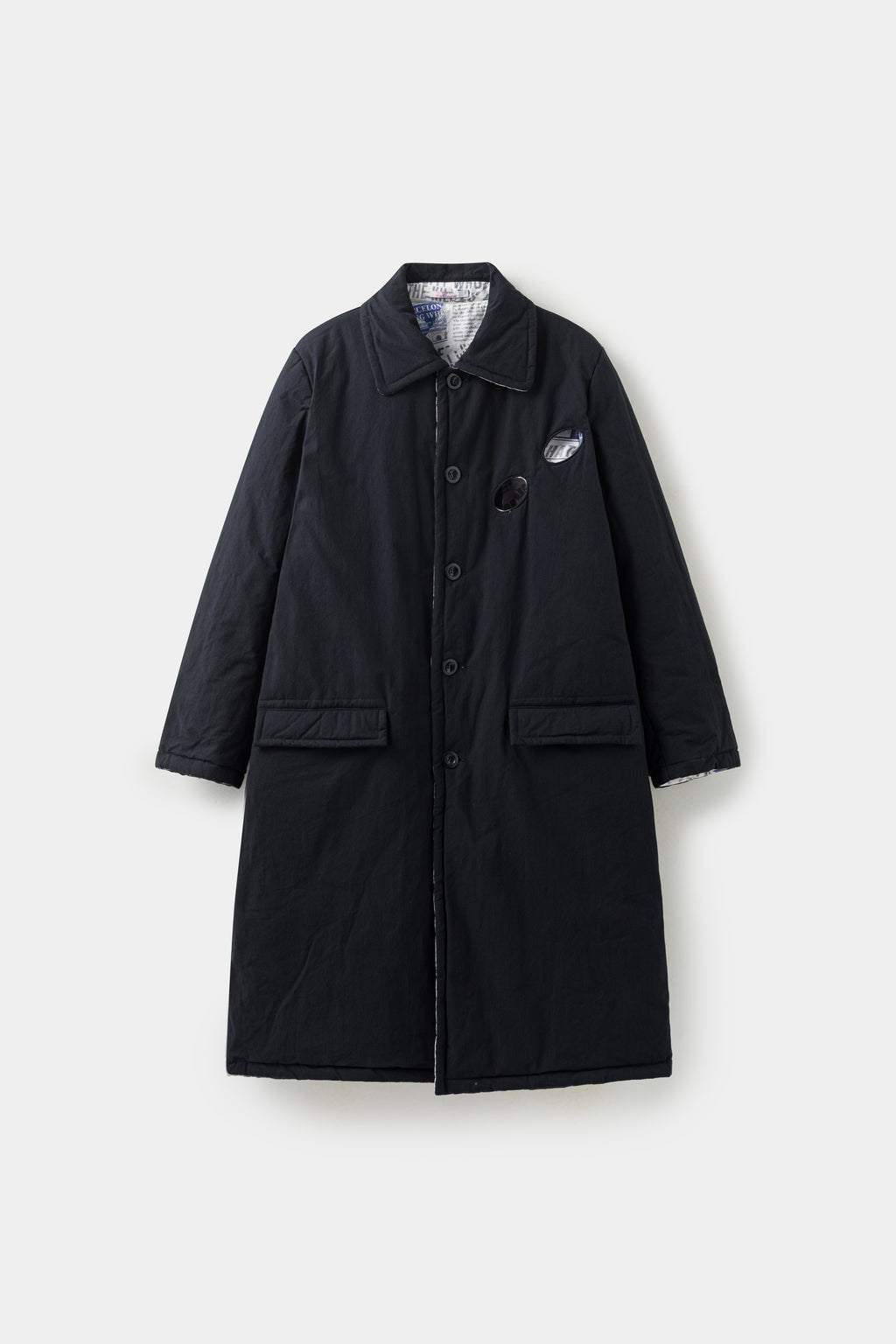 The Newspaper Spy Coat reversed to its plain black side, with flap pockets and a concealed placket.