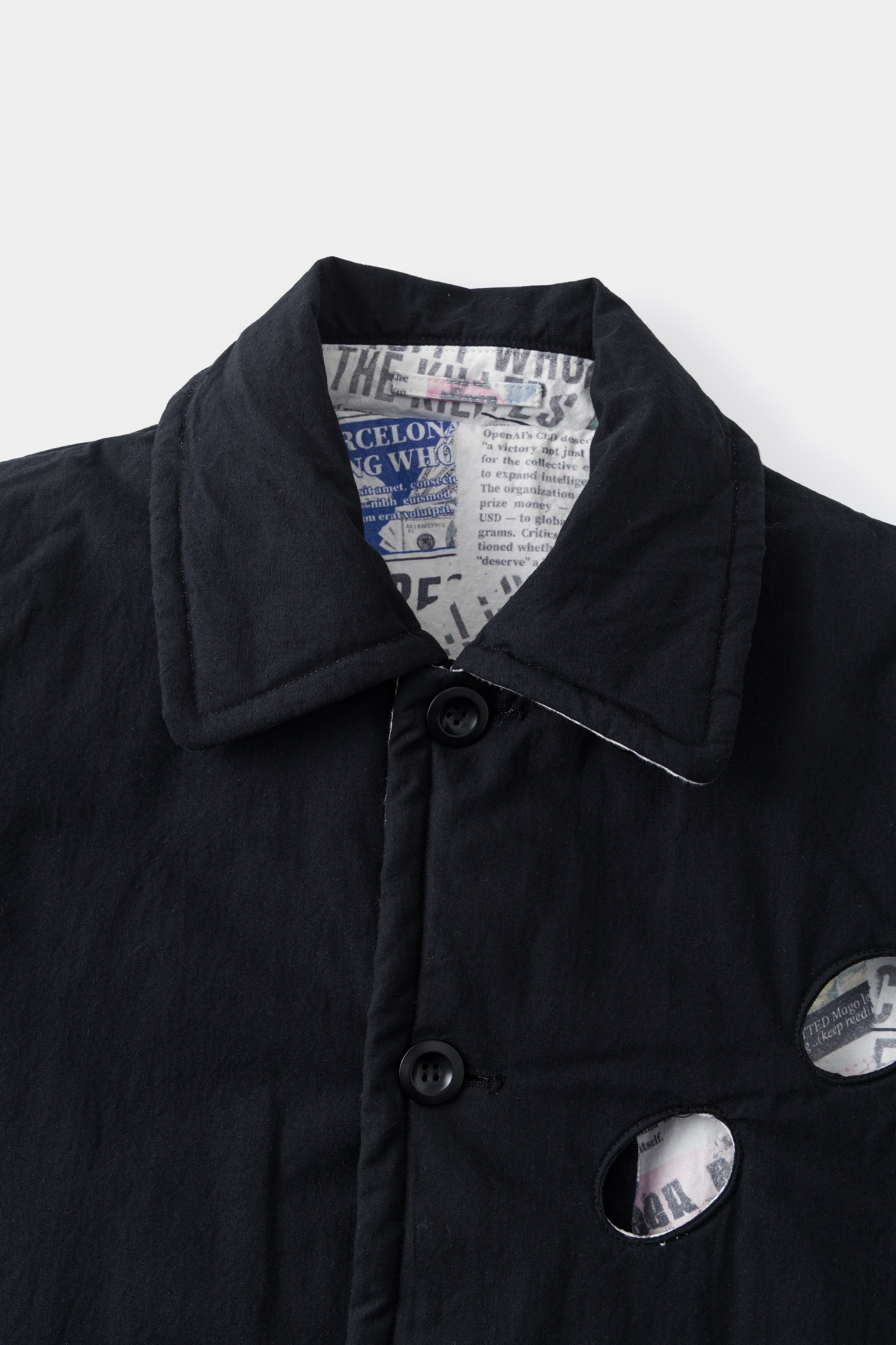 Close-up of the collar and buttons on the black side, with the newsprint lining showing through the eye hole.