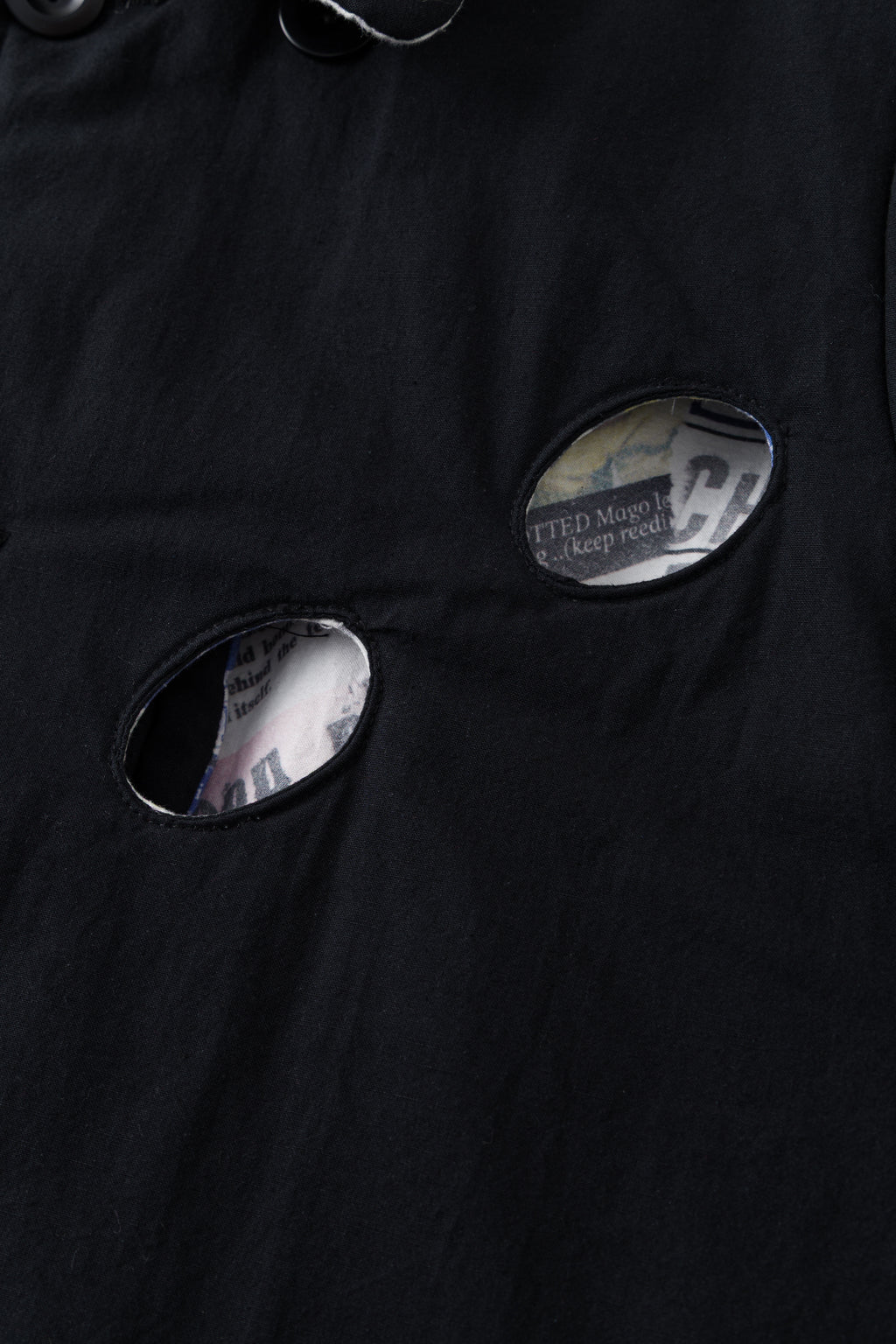Detail of the eye holes on the black side, with the newspaper print visible inside.