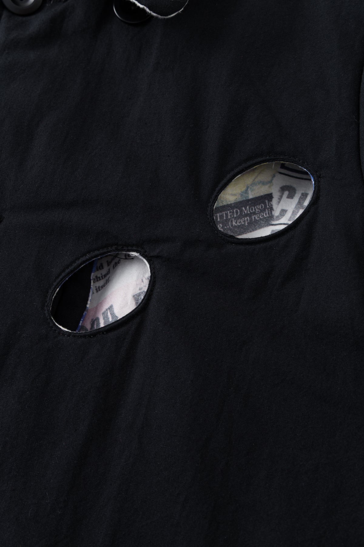 Detail of the eye holes on the black side, with the newspaper print visible inside.