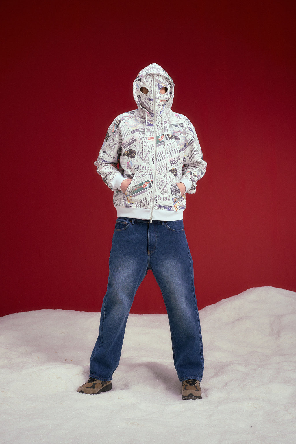 Newspaper Spy Hoodie, a zip-up hoodie printed all over with newsprint. Worn on a model, full-length front view, zipped all the way up over the face.