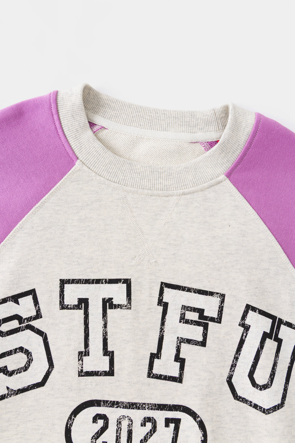Close-up of the ribbed neckline and the raglan seam where the orchid sleeve joins.