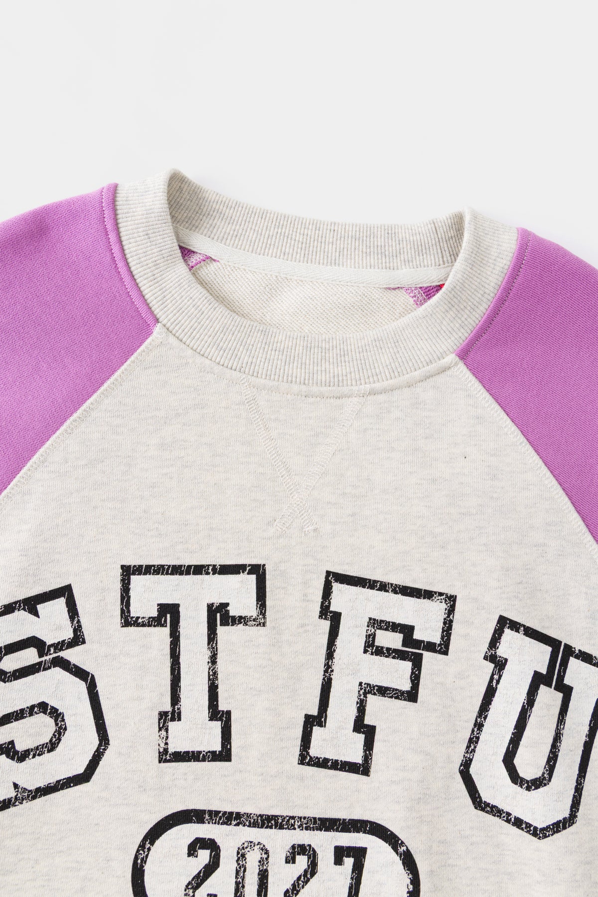 Close-up of the ribbed neckline and the raglan seam where the orchid sleeve joins.