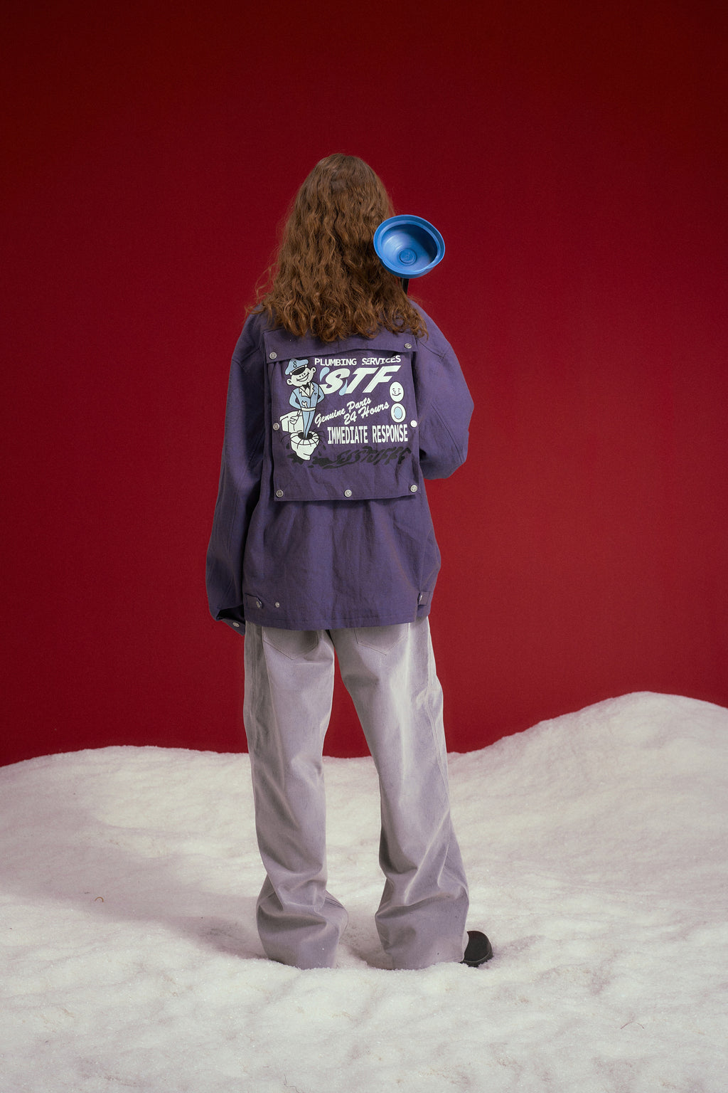 Secret Plumber Jacket in lilac, with velcro chest pockets and a Plumbing Services print at the back. Worn on a model, full-length back view, showing the Plumbing Services print at the back.