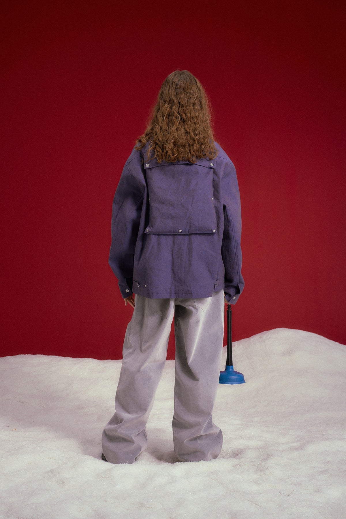 Secret Plumber Jacket in lilac, with velcro chest pockets and a Plumbing Services print at the back. Worn on a model, full-length back view, back pocket flipped open.