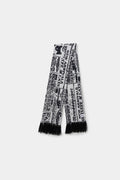 Spy Knitted Scarf in newsprint jacquard, a long scarf with black fringing at both ends.