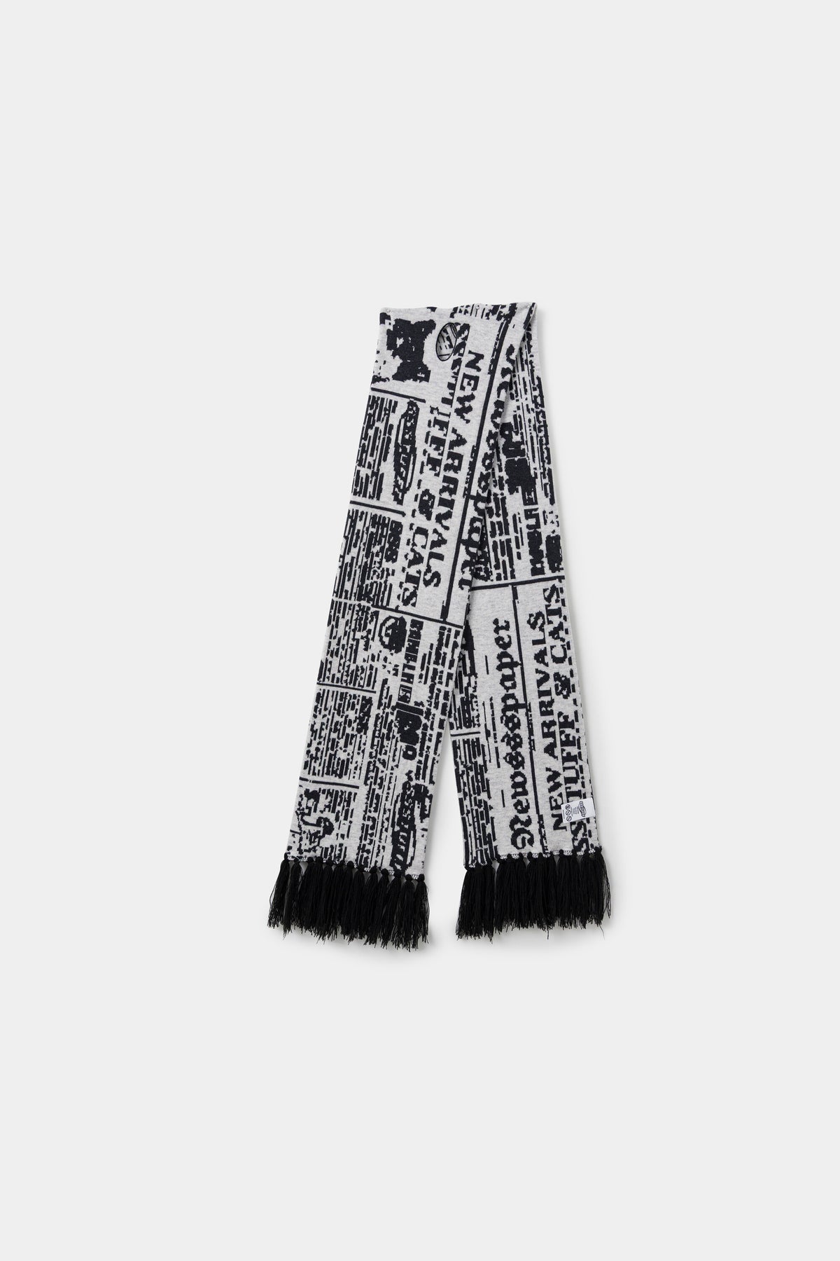 Spy Knitted Scarf in newsprint jacquard, a long scarf with black fringing at both ends.