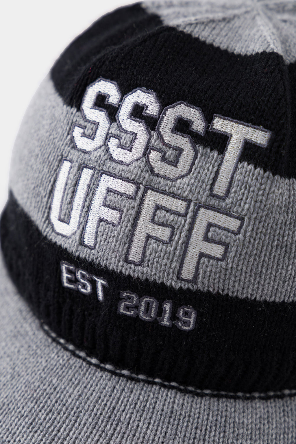 Close-up of the raised SSSTUFFF EST 2019 varsity embroidery across the black and grey stripes.