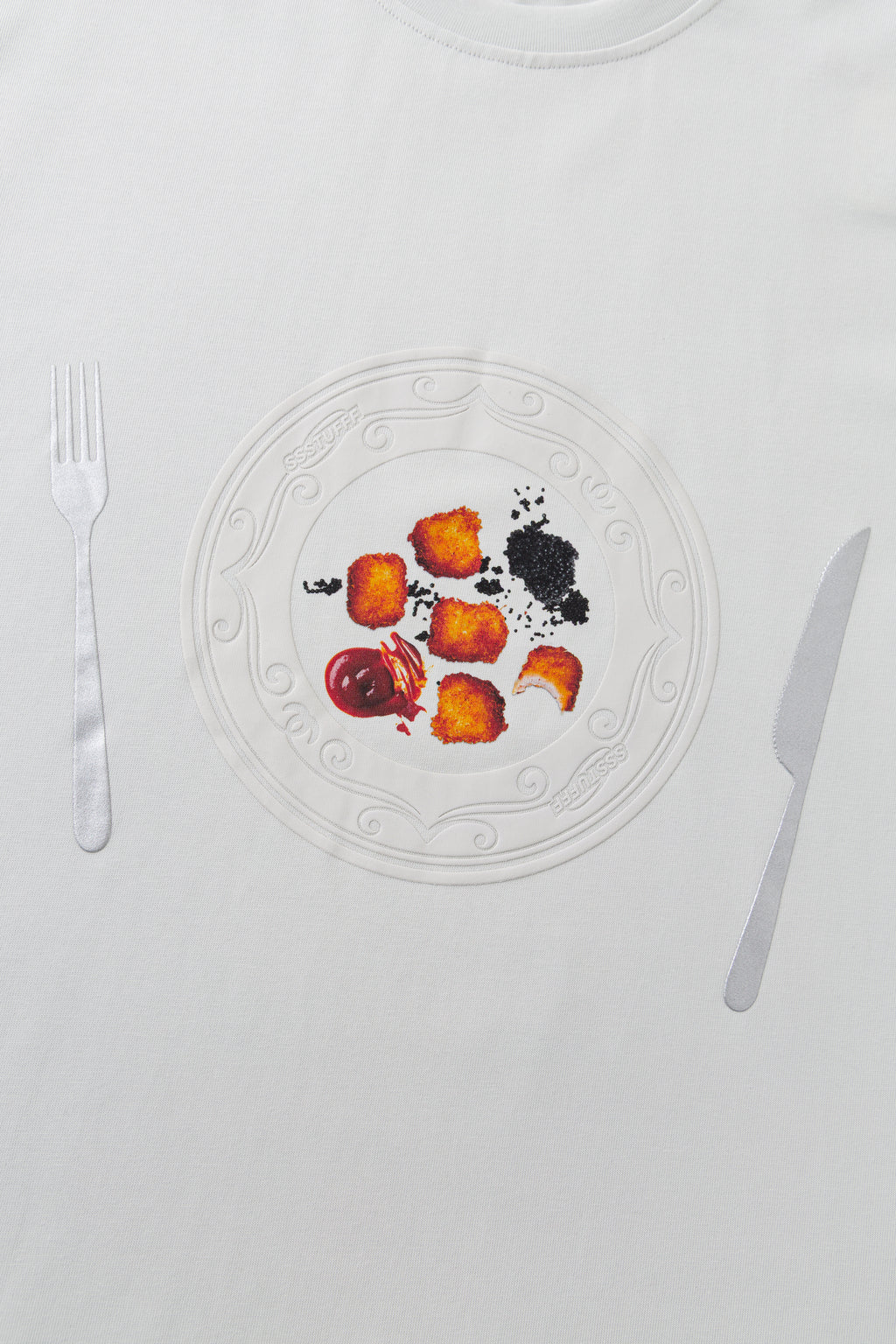 Close-up of the chest print, the embossed dinner plate set between a fork and a knife.