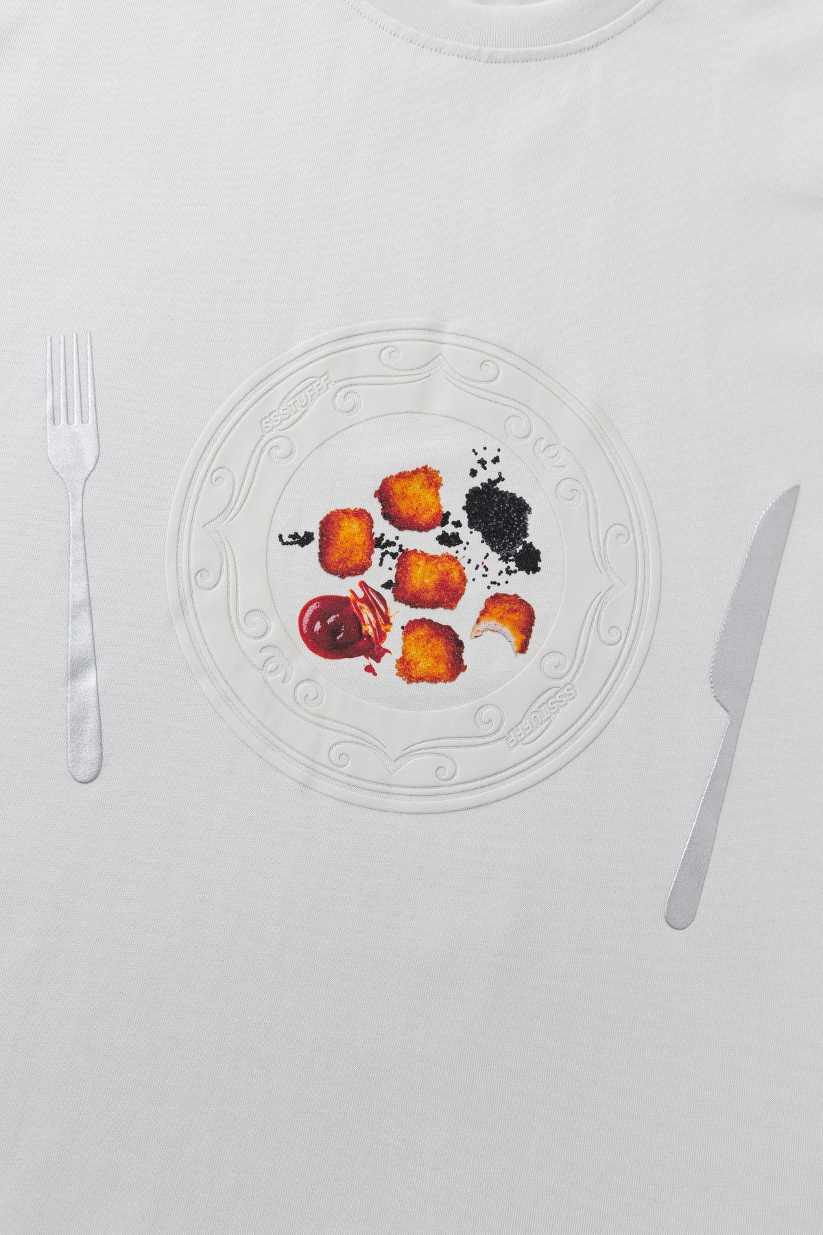 Close-up of the chest print, the embossed dinner plate set between a fork and a knife.