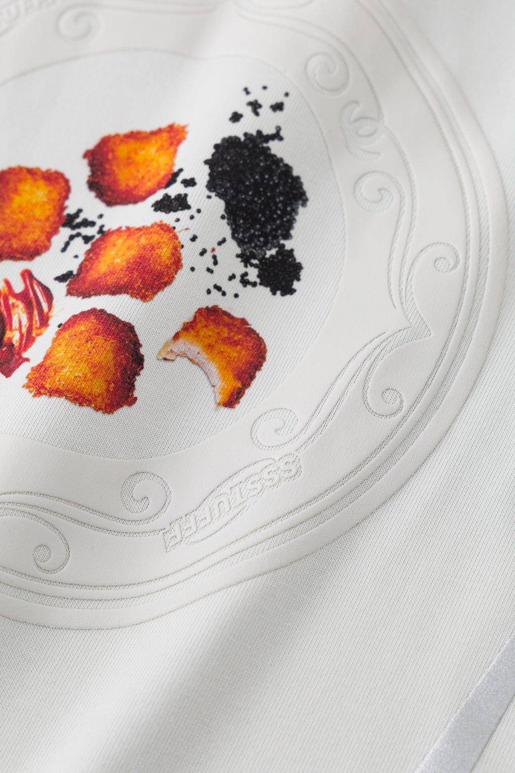 Close-up of the embossed plate: fried bites, sauce and caviar in raised relief, with SSSTUFFF lettering on the rim.