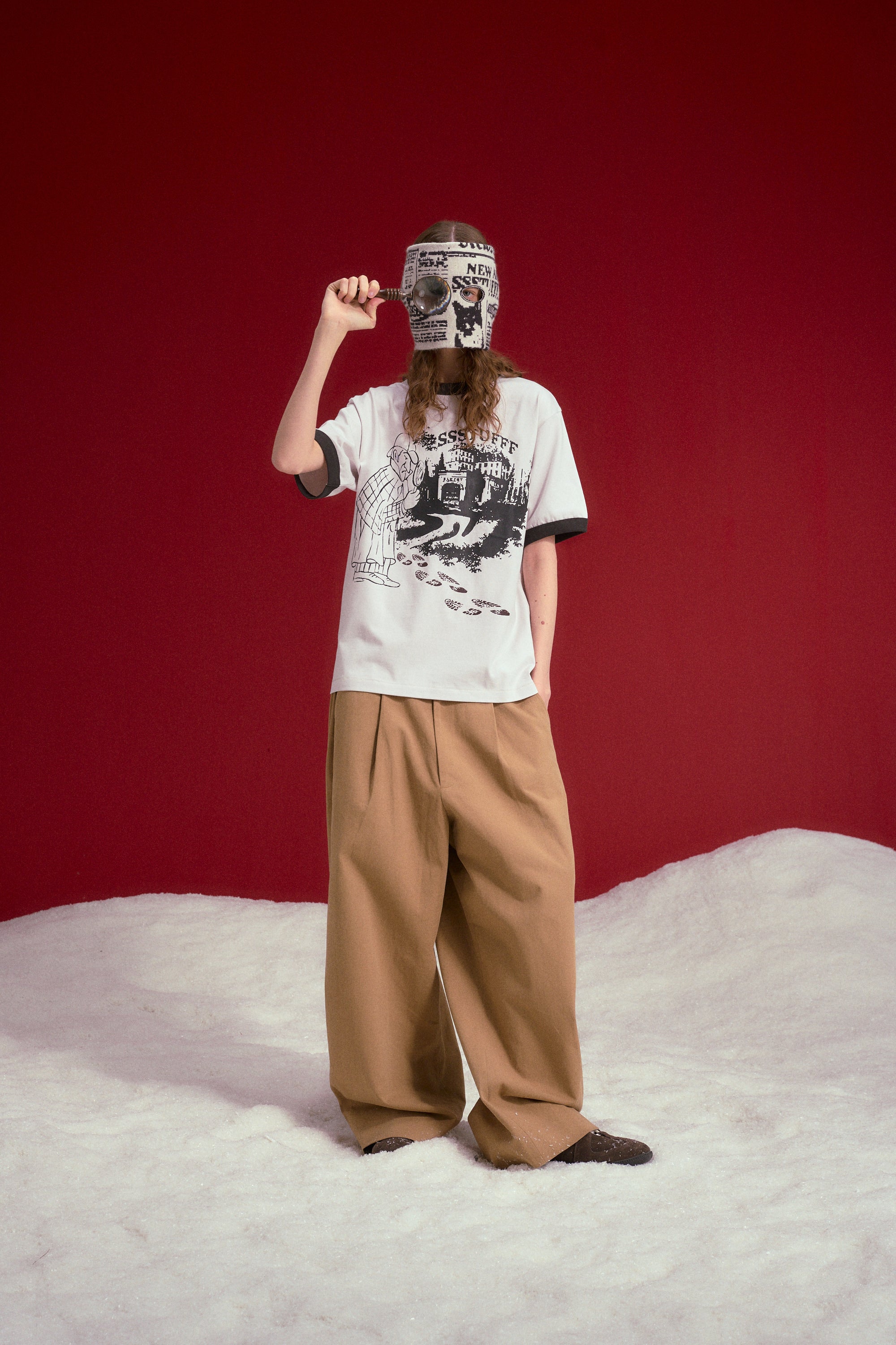 Model wearing the Thermo Reveal Footsteps Tee with wide beige trousers.