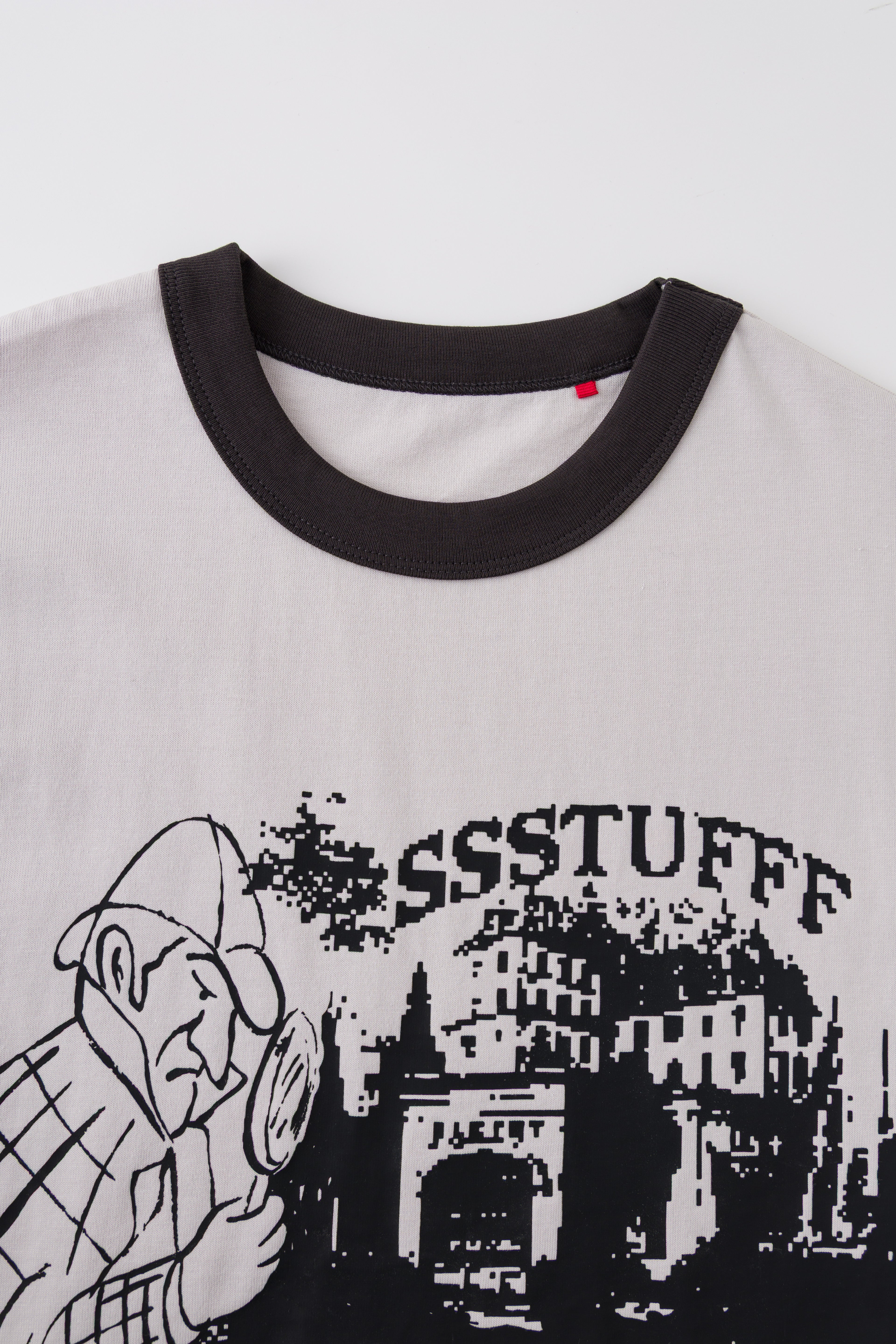 Detail of the black ringer collar and red pin on the Thermo Reveal Footsteps Tee.