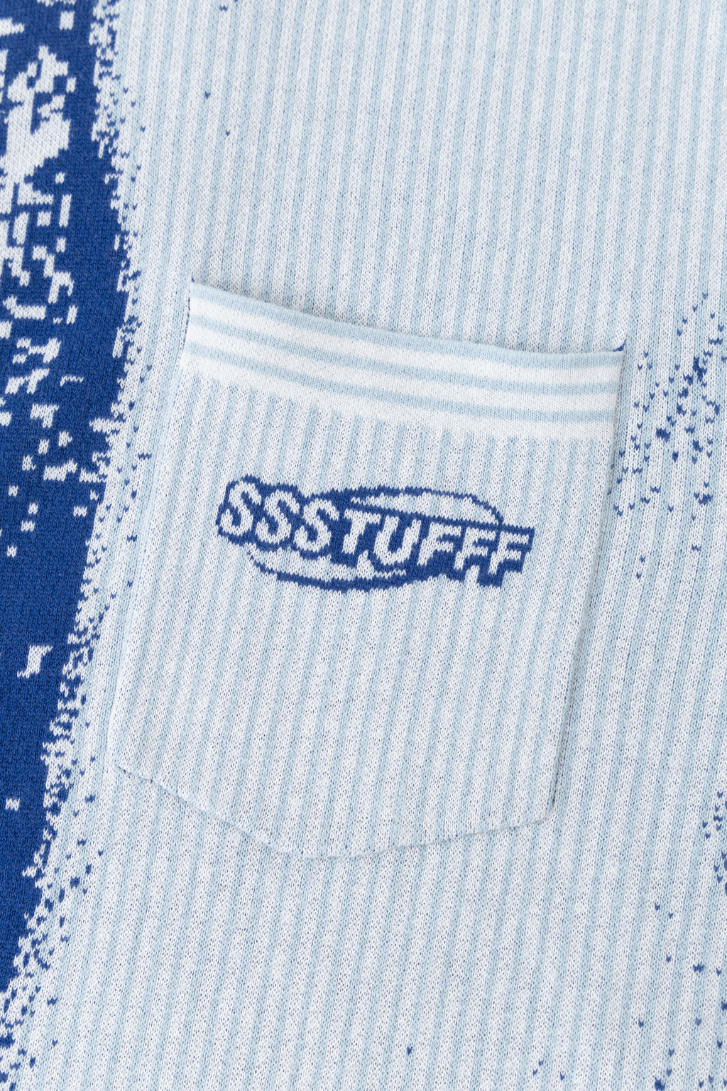 Detail of the knitted chest pocket with the SSSTUFFF logo, beside the blue tie.