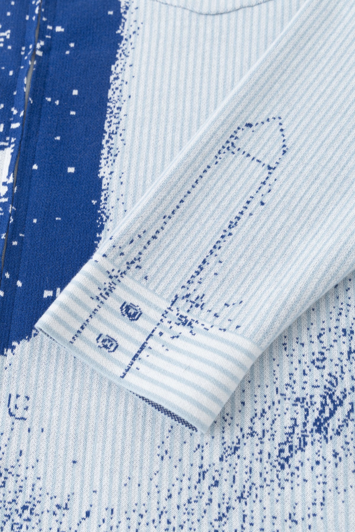Close-up of the striped cuff and the ink splatter knitted along the sleeve.