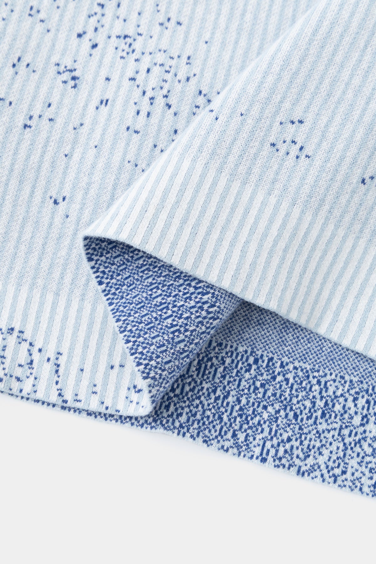Close-up of the hem folded back, showing the reverse of the knit and the blue speckle.