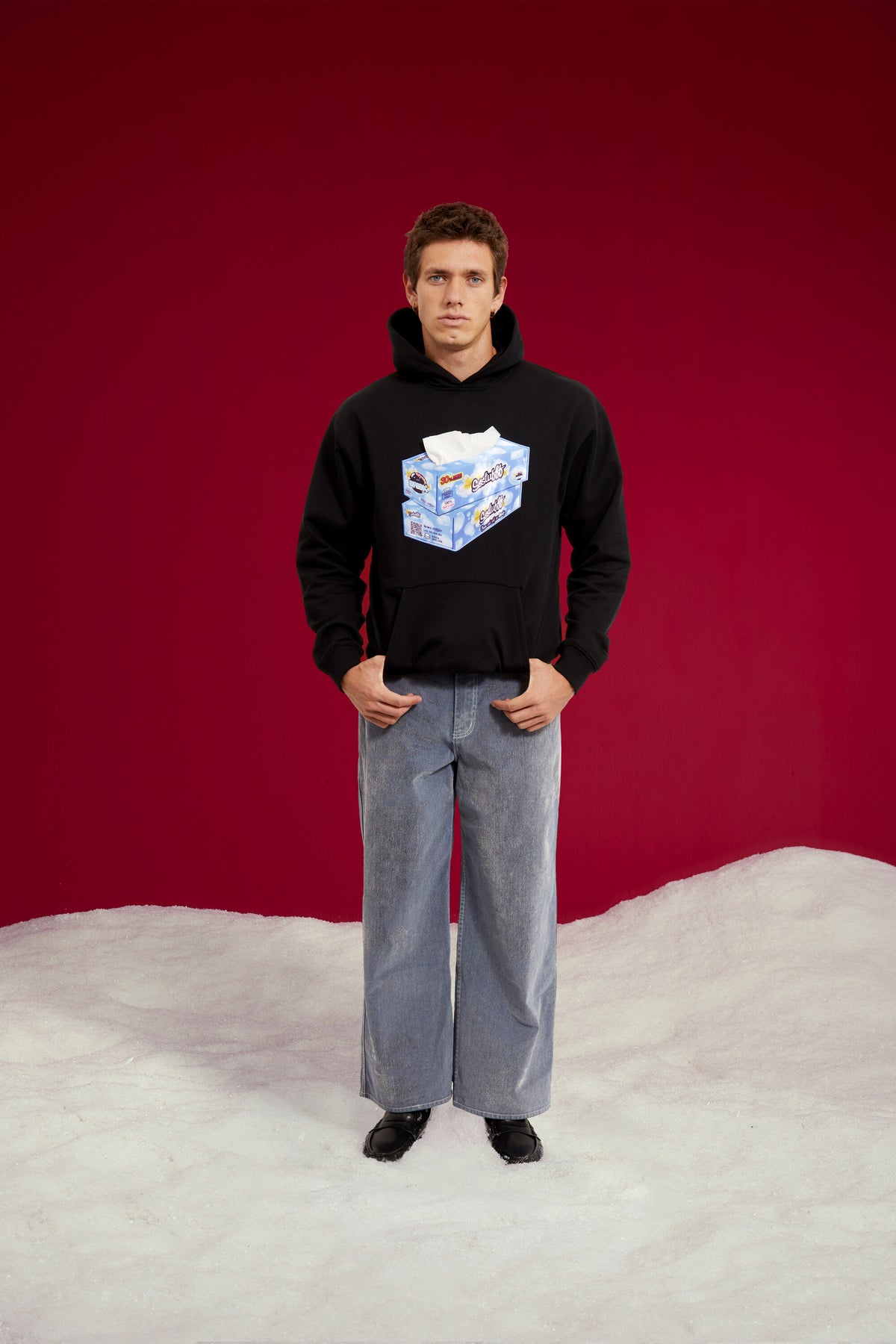 Tissue Hoodie in black, with a 3D tissue box patch sewn onto the chest. Worn on a model, full-length front view.