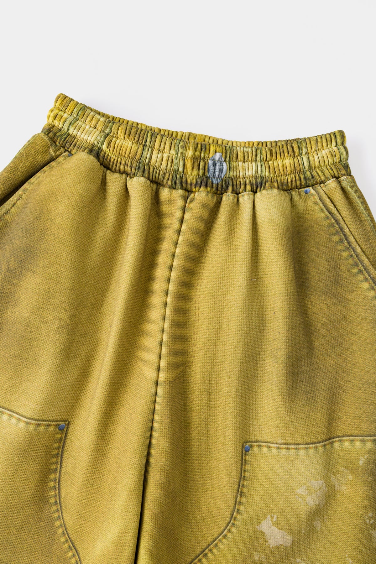 Close-up of the drawstring waistband above the printed front pocket and abrasion shading.