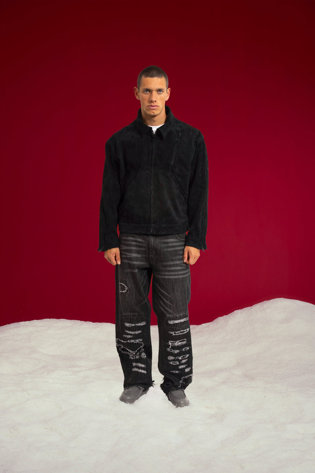 Tyre Track Suede Jacket in black, zipped up over a white tee with black distressed jeans. Worn on a model, full-length front view.