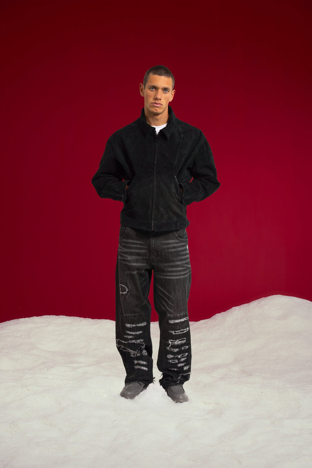 Tyre Track Suede Jacket in black, hands in the slanted welt pockets. Worn on a model, full-length front view.