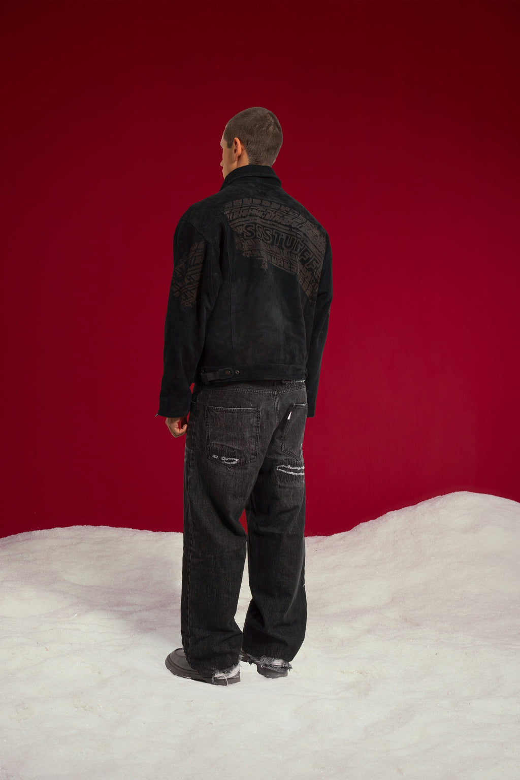 Tyre Track Suede Jacket from behind, the tyre track running across the shoulders. Worn on a model, full-length back three-quarter view.
