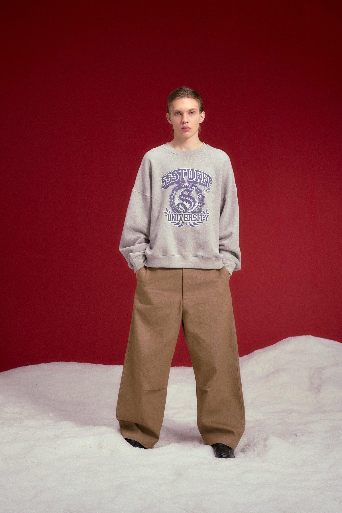 University Logo Crewneck in grey marl, printed with the SSSTUFFF University crest. Worn on a model, full-length front view.