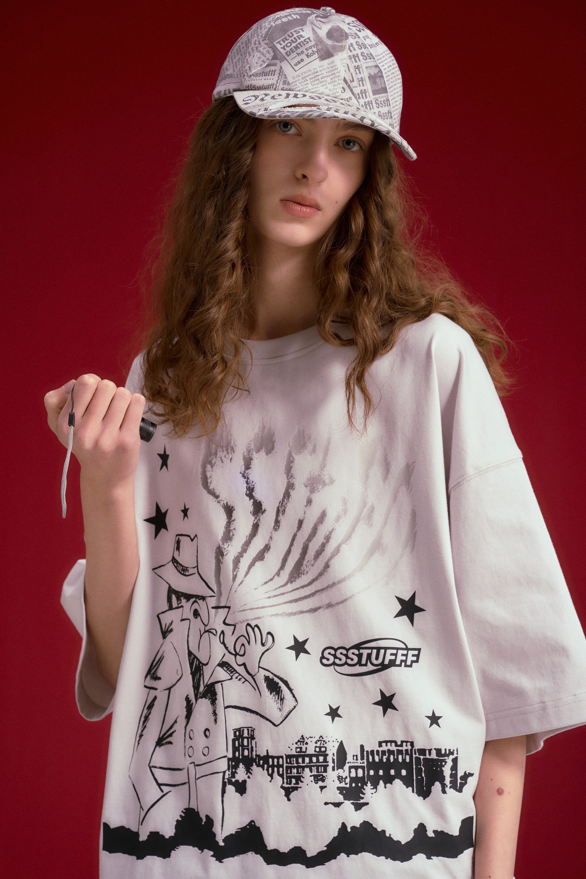 Model wearing the UV Smoking Detective Tee with a newspaper print bucket hat.
