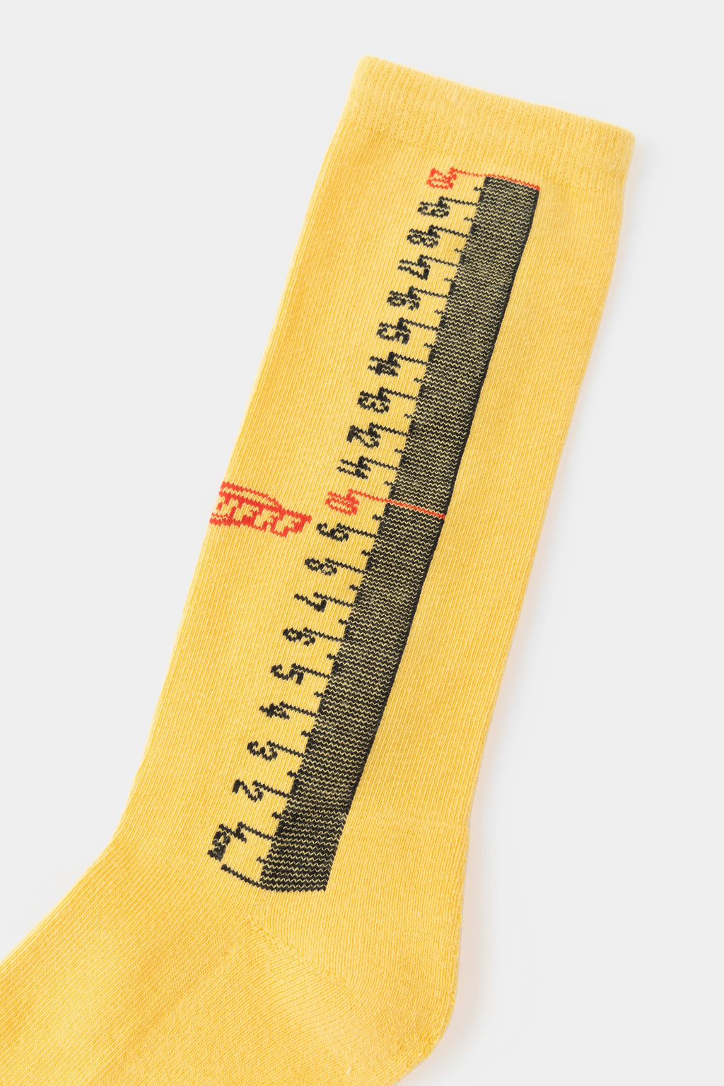 Close-up of the black tape-measure markings knitted down the leg of the yellow sock.
