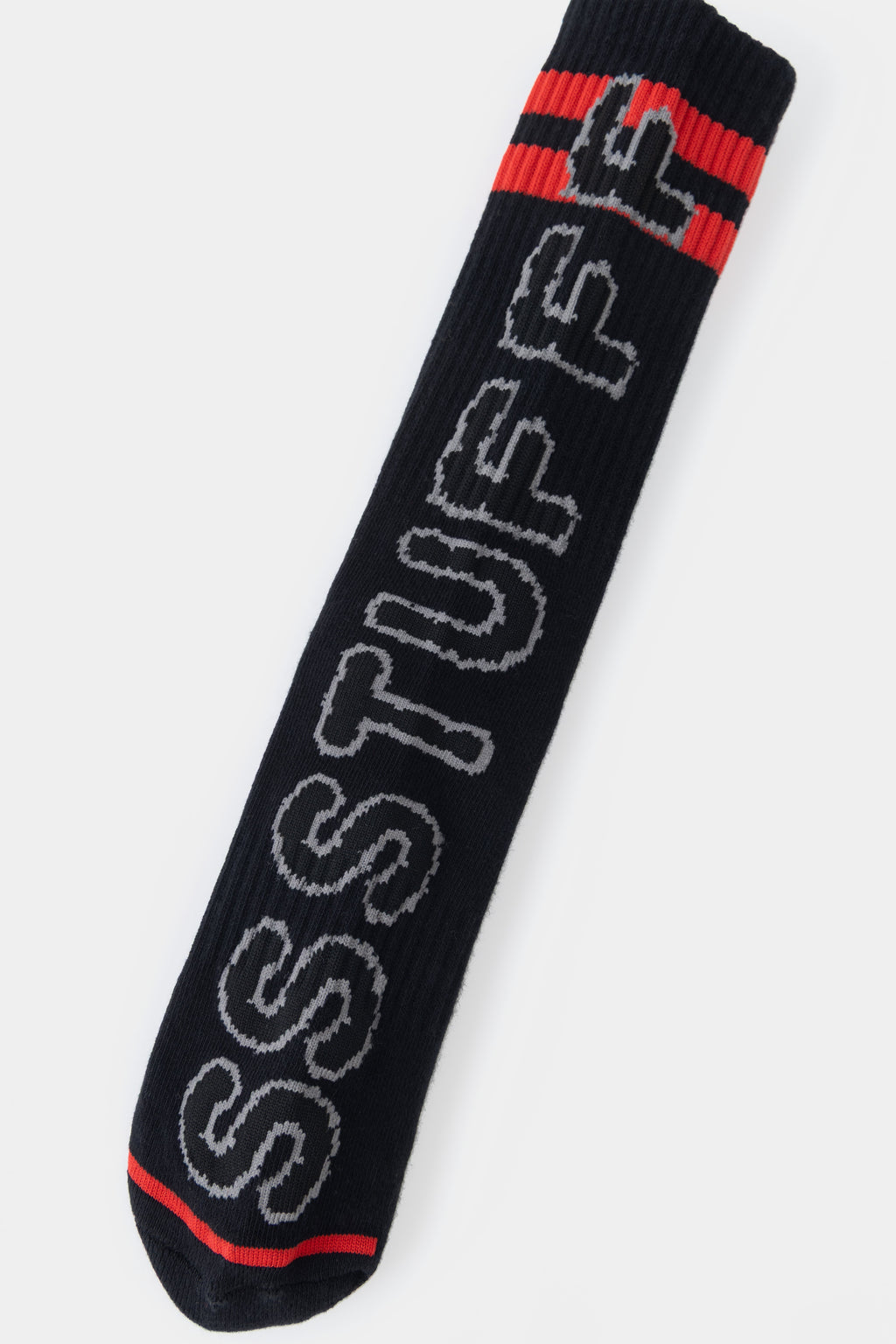 Detail of the SSSTUFFF lettering knitted down the side of the sock, with the red toe below.