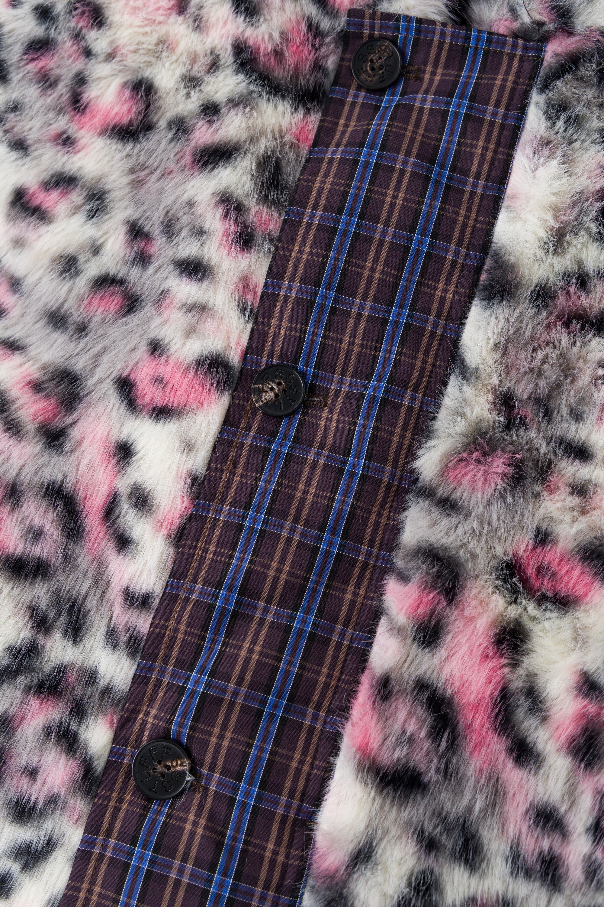Close-up of the buttoned check placket against the pink leopard faux fur.