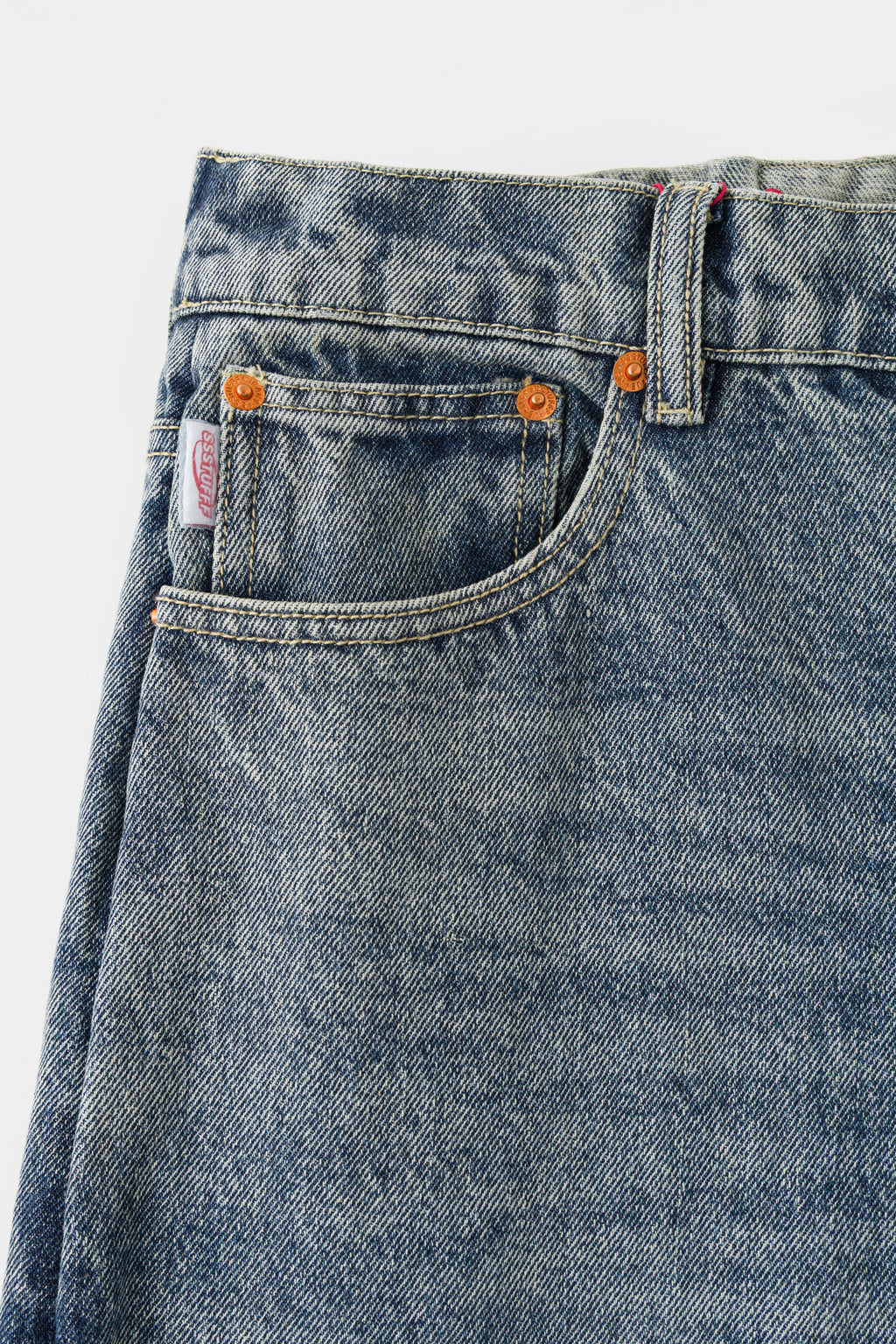 Close-up of the front waistband, coin pocket and orange-tab rivets.