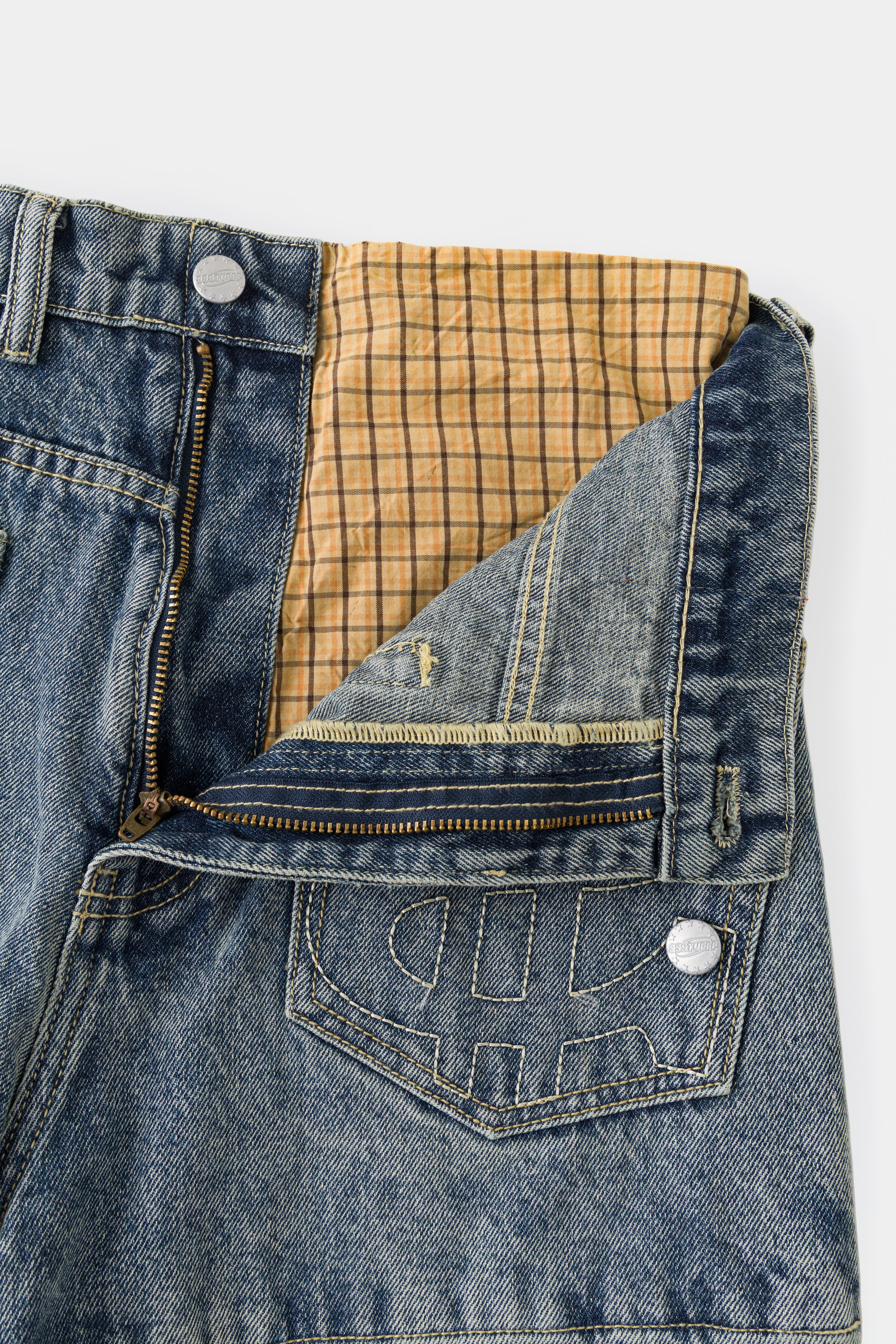Close-up of the front fly opened, showing the checked underwear layer inside the waistband.