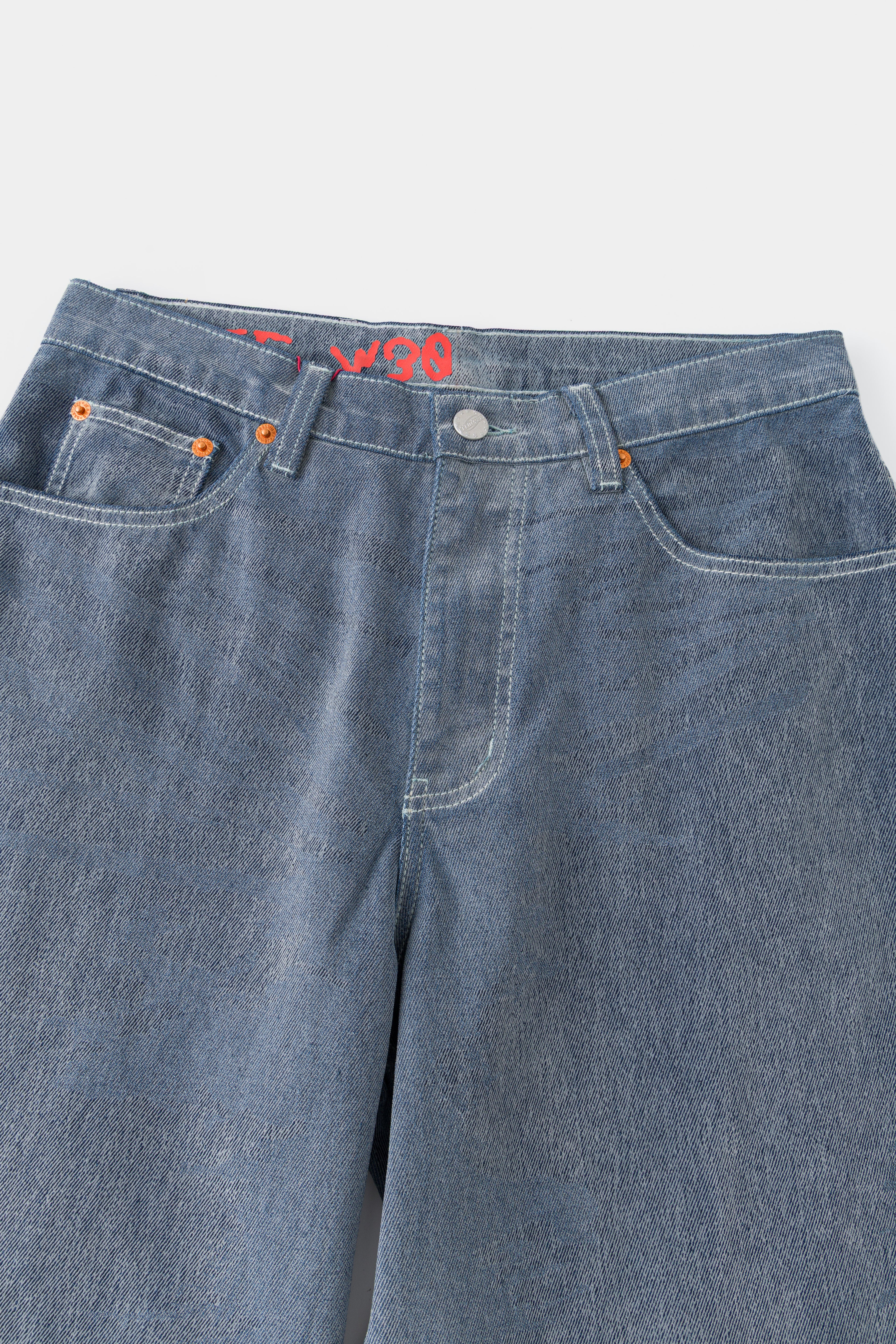 Close-up of the front waistband, button fly and coin pocket on the flocked denim.