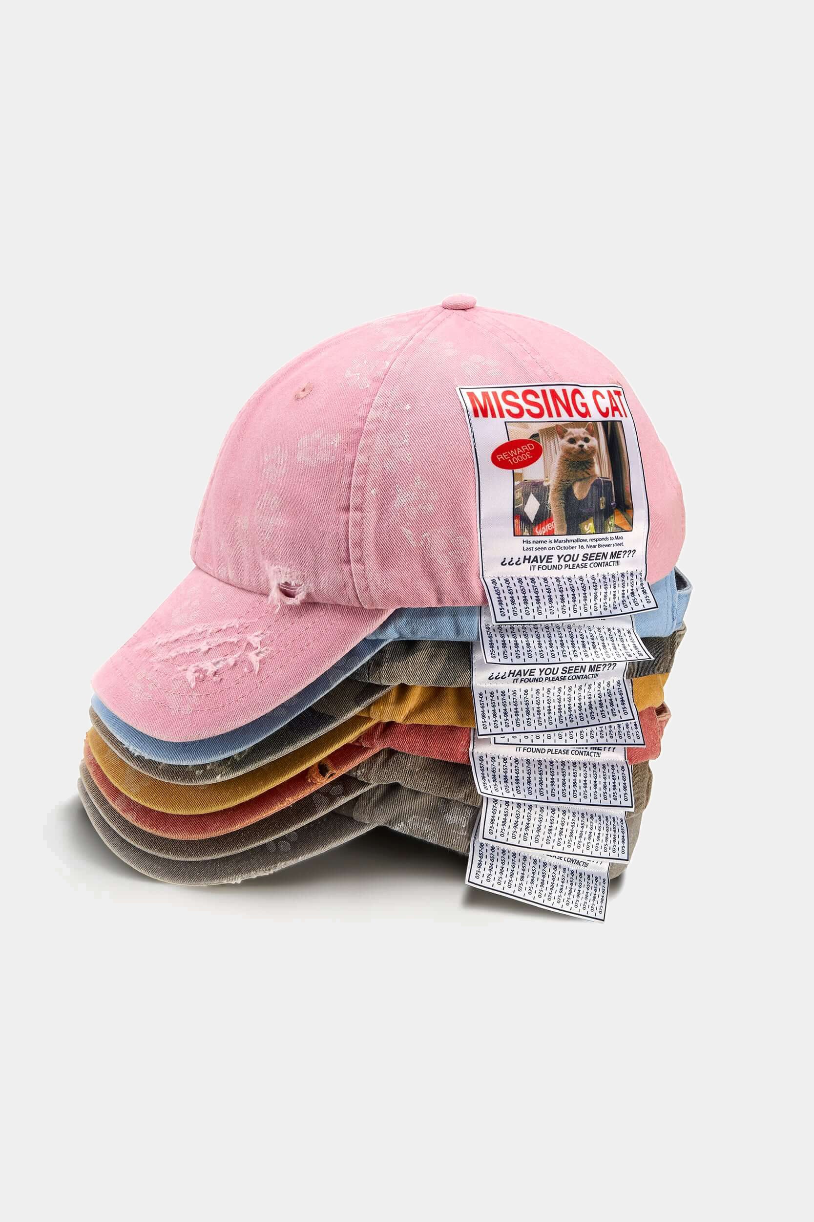 Missing Cat Caps stacked in every colourway, pink on top, each with its MISSING CAT poster patch