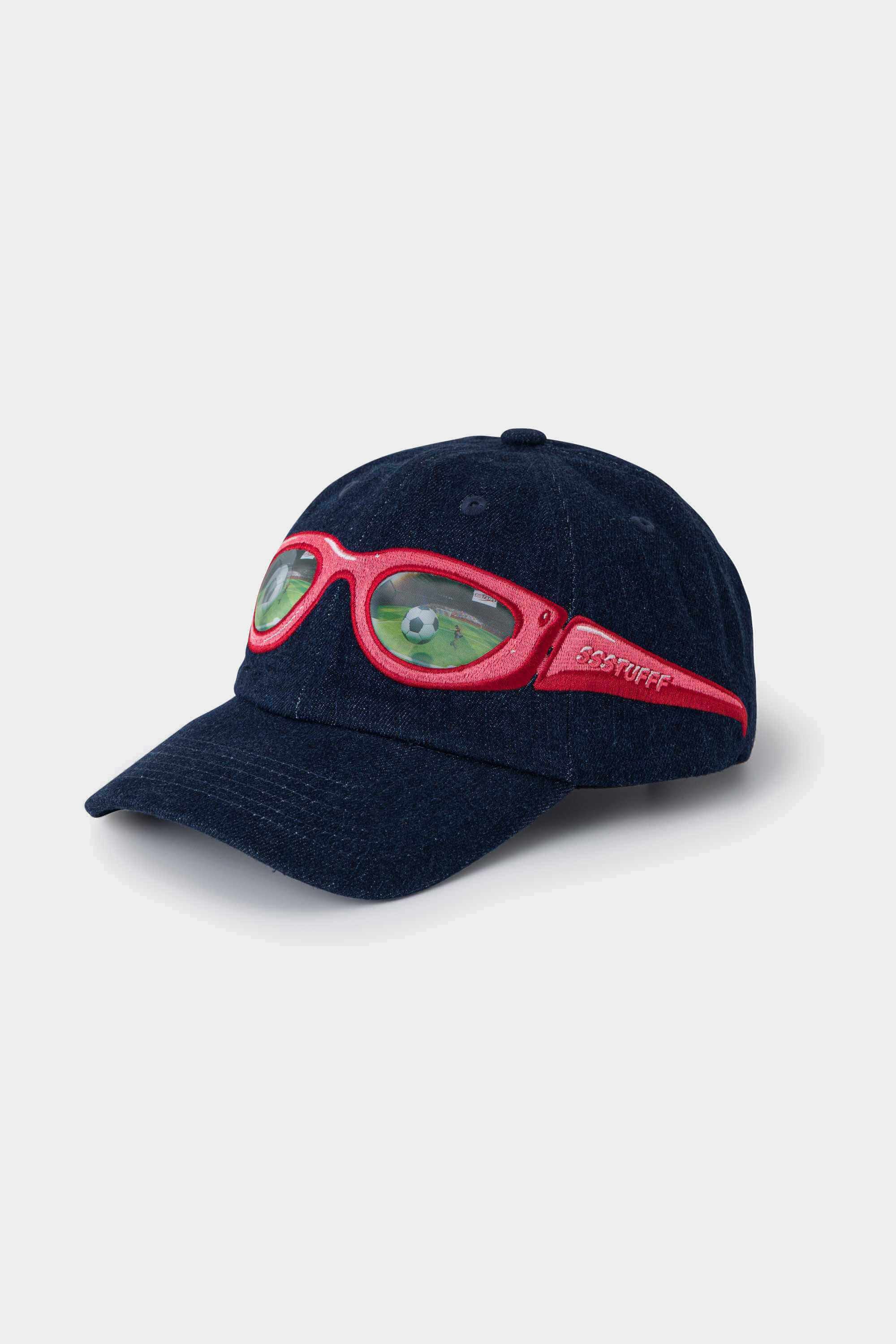 Navy denim cap with a red lenticular sunglasses patch stitched across the front panel and brim