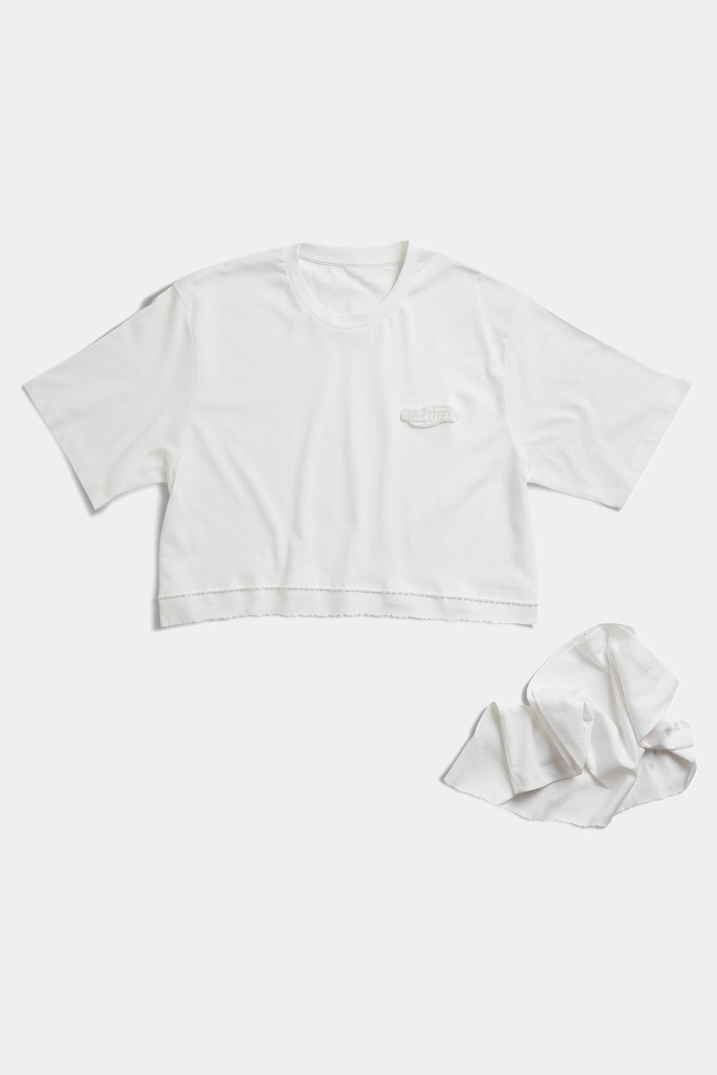 Cropped version of the white FUWARI Embroidery Tee laid flat beside the detached lower panel