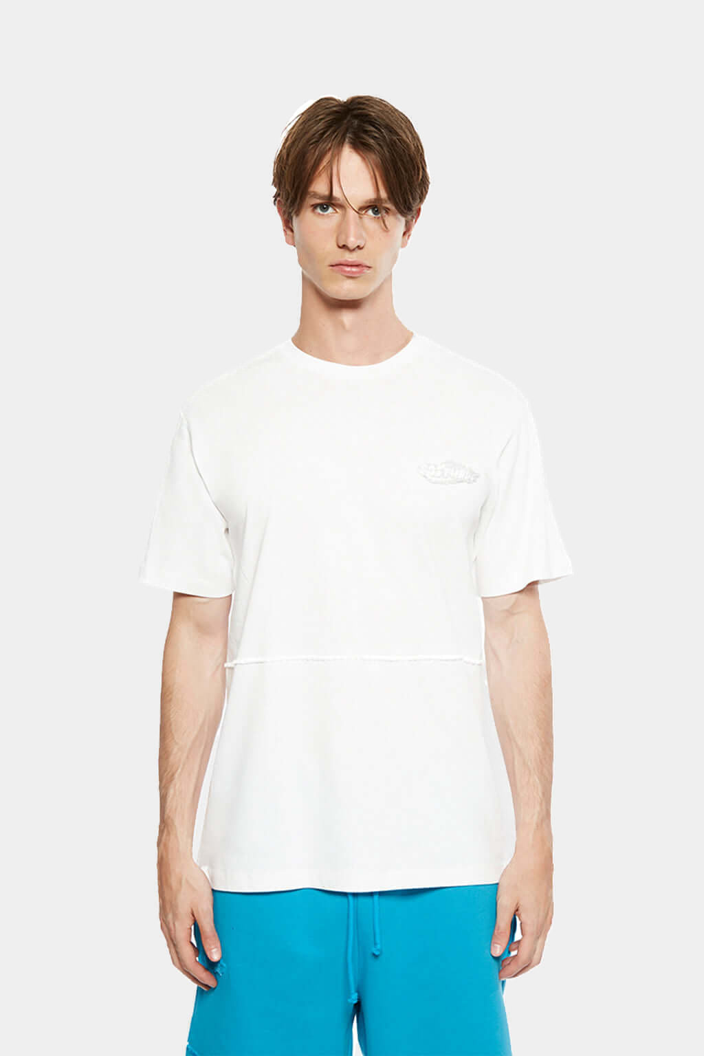 Model wearing the white FUWARI Embroidery Tee with teal shorts
