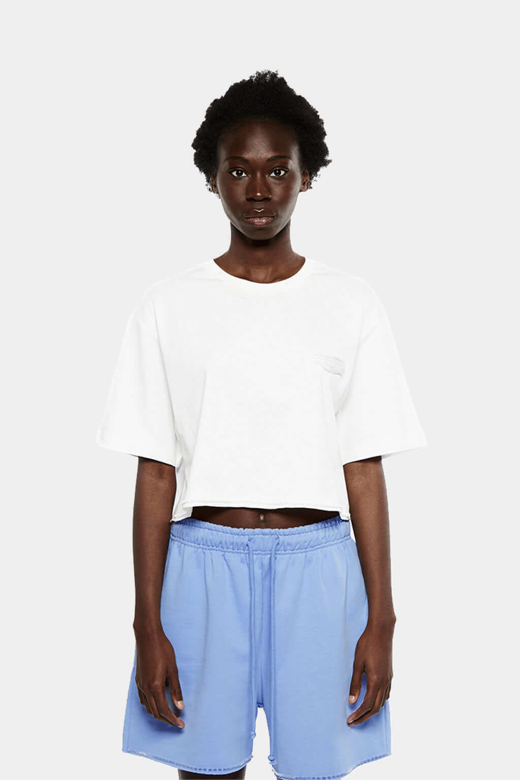 Model wearing the cropped white FUWARI Embroidery Tee with light blue shorts