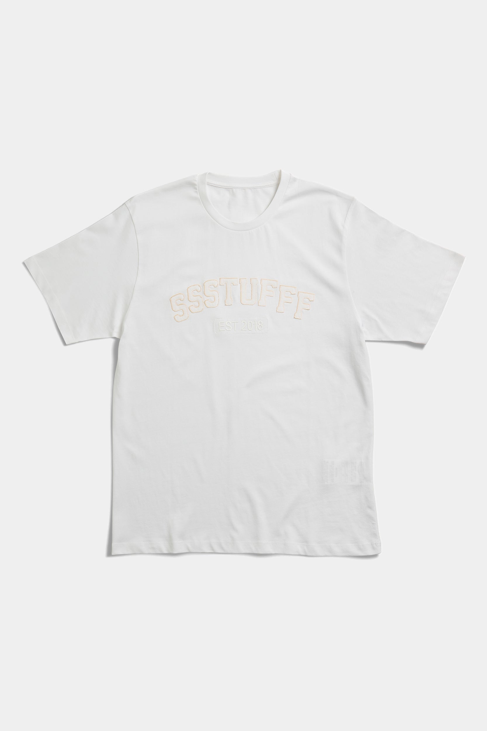 Off-white t-shirt laid flat with tonal embossed SSSTUFFF EST 2018 college lettering across the chest