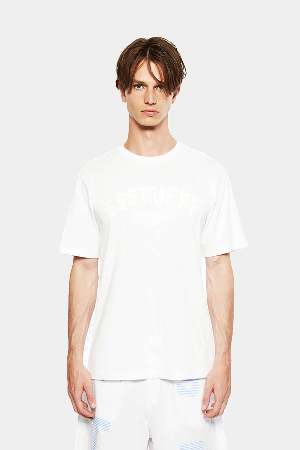 Model wearing the white University Patchwork Tee with white trousers