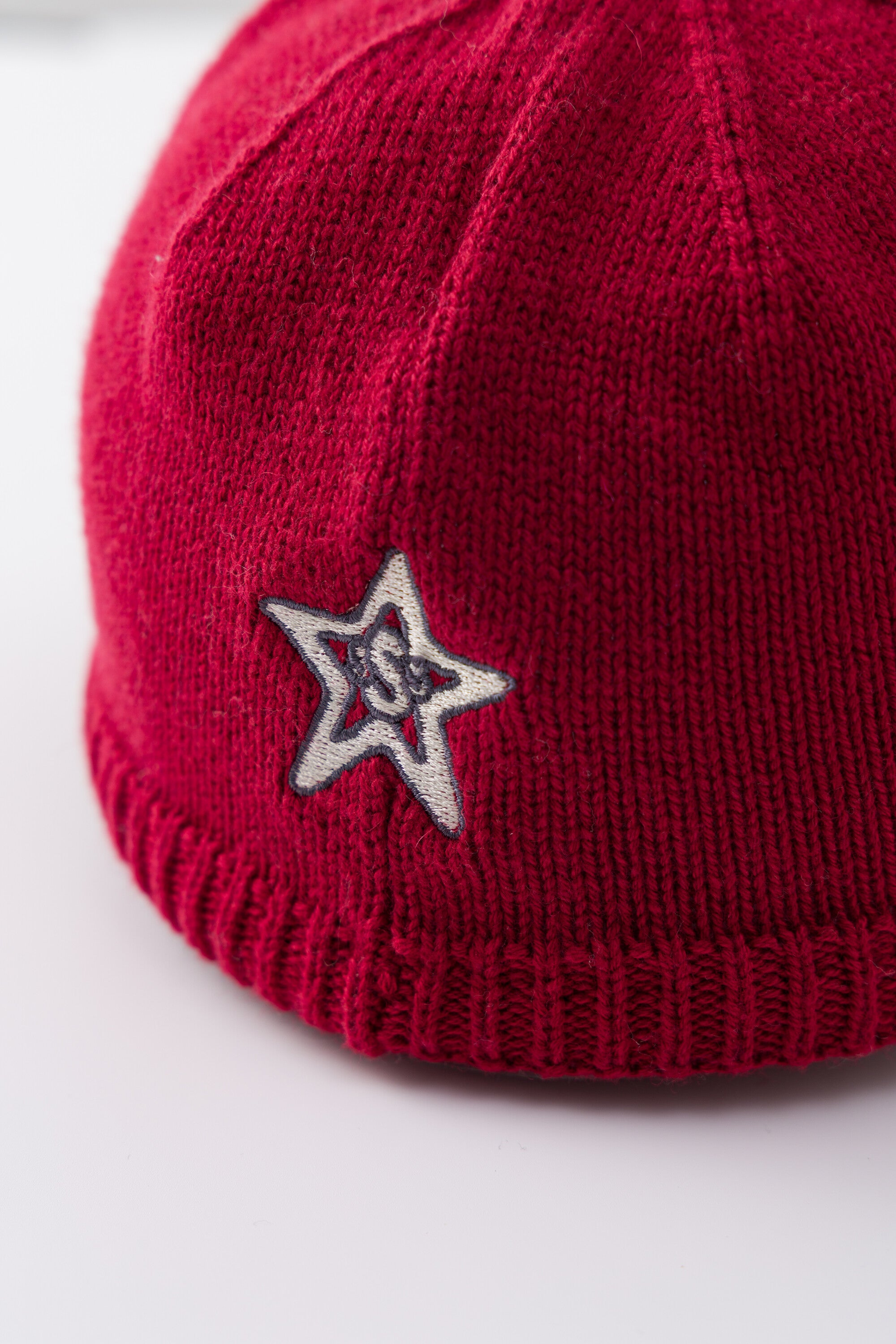 Detail of the embroidered star patch on the side of the red Knitted Cap.